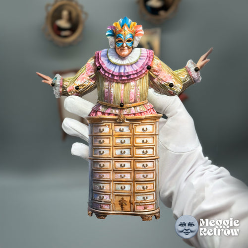 Mystic Bureau, a printable articulated paper doll. A carnival mask and ruffles on top of a wooden cabinet.
