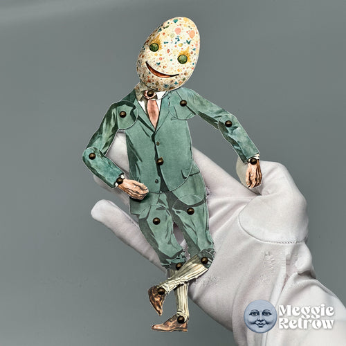 Willie Egg, a printable articulated paper doll. A speckled egg head and a sage-green suit with a pink tie.